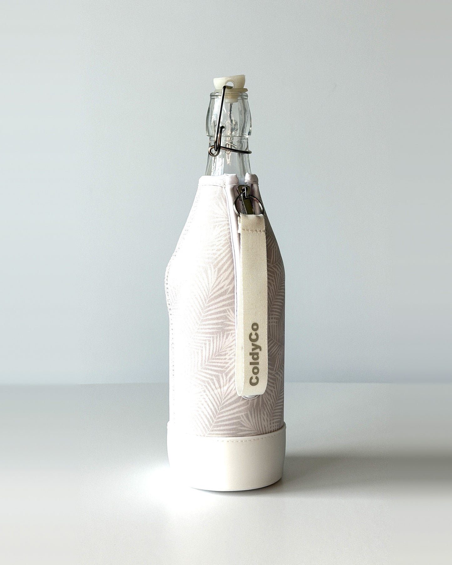 ColdyCo Palm Print bottle carrier holding a swing-top glass bottle, side view